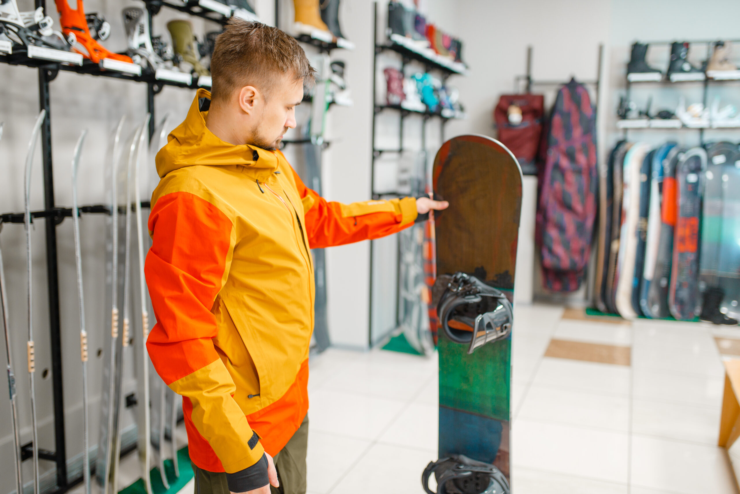 man choosing snowboard, shopping in sports shop